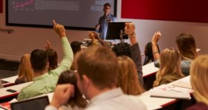 Students at university lecture raise hands to ask questions