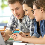 Three students working on a group exam on a laptop