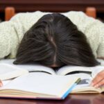 exhausted student face-down in a pile of textbooks