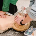 Two women practicing using an automated external defibrillator on a training dummy