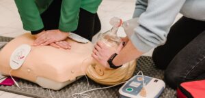 Two women practicing using an automated external defibrillator on a training dummy