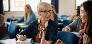 Stock photo of a boomer student talking to a gen z student in class