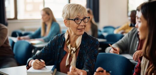 Stock photo of a boomer student talking to a gen z student in class